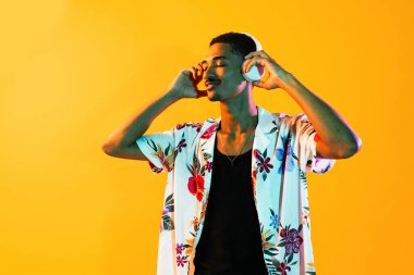 Renkli arka planda Afrikalı genç adam portresi - şık giyinen, yaratıcı renkli ışıklandırmalı havalı siyahi erkek