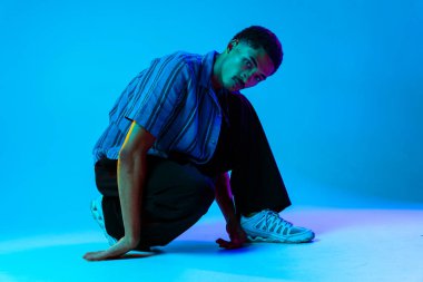 Renkli arka planda Afrikalı genç adam portresi - şık giyinen, yaratıcı renkli ışıklandırmalı havalı siyahi erkek