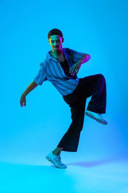 Renkli arka planda Afrikalı genç adam portresi - şık giyinen, yaratıcı renkli ışıklandırmalı havalı siyahi erkek