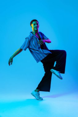 Renkli arka planda Afrikalı genç adam portresi - şık giyinen, yaratıcı renkli ışıklandırmalı havalı siyahi erkek