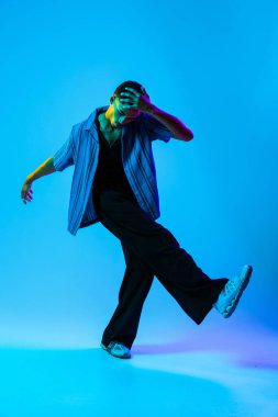 Renkli arka planda Afrikalı genç adam portresi - şık giyinen, yaratıcı renkli ışıklandırmalı havalı siyahi erkek