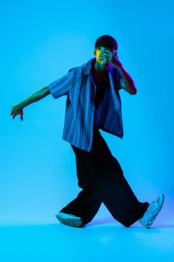 Renkli arka planda Afrikalı genç adam portresi - şık giyinen, yaratıcı renkli ışıklandırmalı havalı siyahi erkek