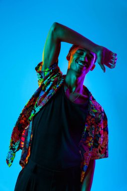 Renkli arka planda Afrikalı genç adam portresi - şık giyinen, yaratıcı renkli ışıklandırmalı havalı siyahi erkek