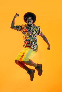 Renkli arka planda Afrikalı adam portresi - şık giyinen havalı siyah erkek, yaratıcı renkli ışıklandırma