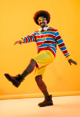 Renkli arka planda Afrikalı adam portresi - şık giyinen havalı siyah erkek, yaratıcı renkli ışıklandırma