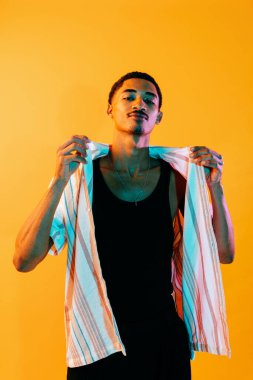 Renkli arka planda Afrikalı genç adam portresi - şık giyinen havalı siyah erkek, yaratıcı renkli ışıklandırma