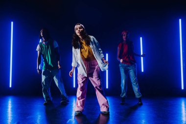Bir grup hip hop dansçısı neon ışıklarıyla kasvetli bir stüdyoda dans ediyorlar..