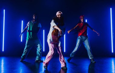 Bir grup hip hop dansçısı neon ışıklarıyla kasvetli bir stüdyoda dans ediyorlar..