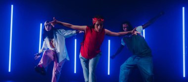 Bir grup hip hop dansçısı neon ışıklarıyla kasvetli bir stüdyoda dans ediyorlar..