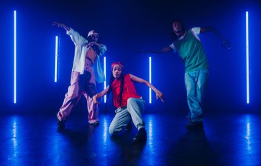 Bir grup hip hop dansçısı neon ışıklarıyla kasvetli bir stüdyoda dans ediyorlar..