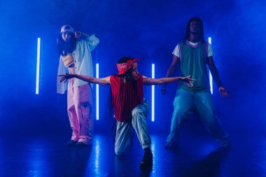 Bir grup hip hop dansçısı neon ışıklarıyla kasvetli bir stüdyoda dans ediyorlar..