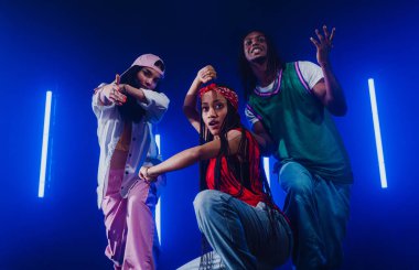 Bir grup hip hop dansçısı neon ışıklarıyla kasvetli bir stüdyoda dans ediyorlar..