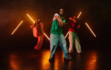 Bir grup hip hop dansçısı neon ışıklarıyla kasvetli bir stüdyoda dans ediyorlar..