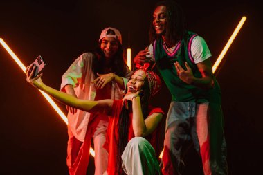 Hip hop dansçılarından oluşan bir grup, neon ışıklarıyla kasvetli bir stüdyoda dans ediyorlar. Ara verdiğimizde selfie çekiyoruz..