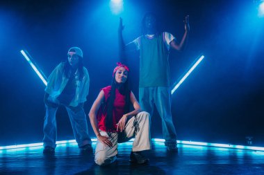 Bir grup hip hop dansçısı neon ışıklarıyla kasvetli bir stüdyoda dans ediyorlar..