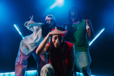 Bir grup hip hop dansçısı neon ışıklarıyla kasvetli bir stüdyoda dans ediyorlar..
