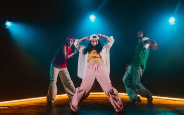 Bir grup hip hop dansçısı neon ışıklarıyla kasvetli bir stüdyoda dans ediyorlar..