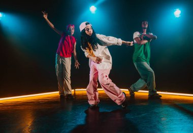 Bir grup hip hop dansçısı neon ışıklarıyla kasvetli bir stüdyoda dans ediyorlar..