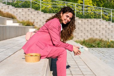 Şık takım elbiseli, güzel, genç bir iş kadını şehirde geziyor, neşeli, beyaz bir kadın ofiste çalışıyor.