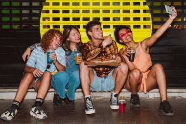 Arkadaşların akşam dışarı çıkıp parti yapıyor. Gençler hafta sonları dışarıda buluşup renkli kokteyller ve pizzayla kutlama yapıyorlar. Ön flaş fotoğraf biçimi.