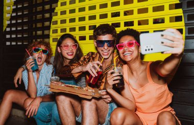 Arkadaşların akşam dışarı çıkıp parti yapıyor. Gençler hafta sonları dışarıda buluşup renkli kokteyller ve pizzayla kutlama yapıyorlar. Ön flaş fotoğraf biçimi.