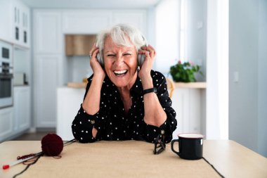 Evde gri saçlı, kulaklıkla müzik dinlerken şarkı söyleyen yaşlı ve güzel bir kadın. Genç, yaşlı büyükanne evde kaliteli vakit geçiriyor.