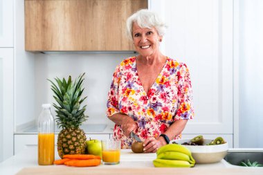 Gri saçlı, evde meyve yiyen yaşlı ve güzel yaşlı bir kadın. Genç, yaşlı bir büyükanne evde kaliteli zaman geçiriyor.