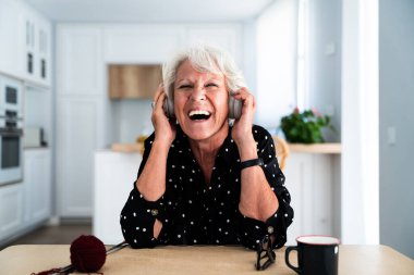 Evde gri saçlı, kulaklıkla müzik dinlerken şarkı söyleyen yaşlı ve güzel bir kadın. Genç, yaşlı büyükanne evde kaliteli vakit geçiriyor.