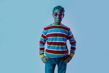 Stüdyoda poz veren kıdemli adam. Renkli arka planlarda farklı ifadeler takınan komik kıdemli adam. Renkli jel ışıklarıyla stüdyo çekimi.