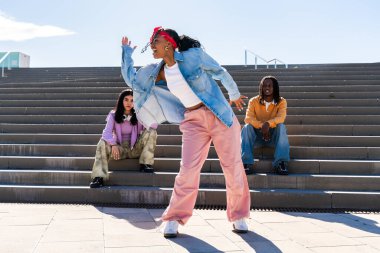 Young group of multiethnic hip-hop dancers wearing colorful urban streetwear dancing - Stylish multiracial rap crew portrait in the city clipart