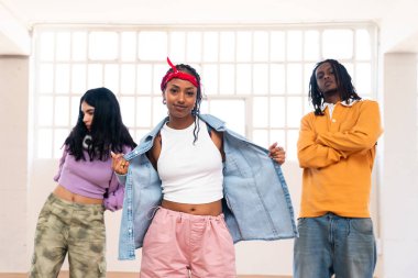 Çok ırklı hip-hop dansçılarından oluşan genç bir grup renkli sokak kıyafetleri giyip dans ediyorlar.