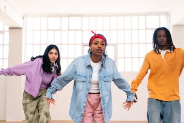Çok ırklı hip-hop dansçılarından oluşan genç bir grup renkli sokak kıyafetleri giyip dans ediyorlar.