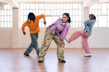 Çok ırklı hip-hop dansçılarından oluşan genç bir grup renkli sokak kıyafetleri giyip dans ediyorlar.