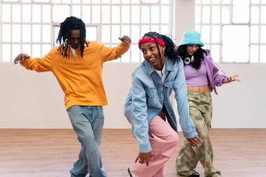 Çok ırklı hip-hop dansçılarından oluşan genç bir grup renkli sokak kıyafetleri giyip dans ediyorlar.