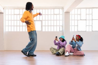 Young group of multiethnic hip-hop dancers wearing colorful urban streetwear dancing - Stylish multiracial rap crew portrait in the dance studio clipart