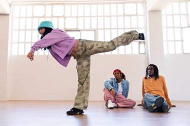 Çok ırklı hip-hop dansçılarından oluşan genç bir grup renkli sokak kıyafetleri giyip dans ediyorlar.