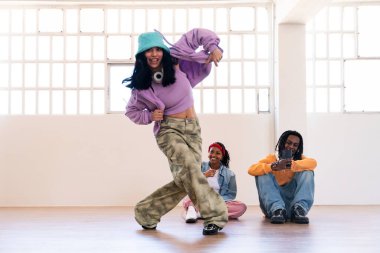 Çok ırklı hip-hop dansçılarından oluşan genç bir grup renkli sokak kıyafetleri giyip dans ediyorlar.