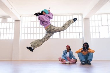 Çok ırklı hip-hop dansçılarından oluşan genç bir grup renkli sokak kıyafetleri giyip dans ediyorlar.