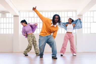 Çok ırklı hip-hop dansçılarından oluşan genç bir grup renkli sokak kıyafetleri giyip dans ediyorlar.
