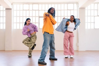 Çok ırklı hip-hop dansçılarından oluşan genç bir grup renkli sokak kıyafetleri giyip dans ediyorlar.