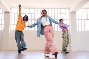 Çok ırklı hip-hop dansçılarından oluşan genç bir grup renkli sokak kıyafetleri giyip dans ediyorlar.