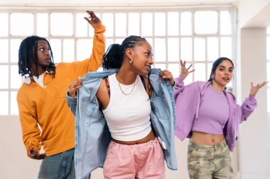 Çok ırklı hip-hop dansçılarından oluşan genç bir grup renkli sokak kıyafetleri giyip dans ediyorlar.
