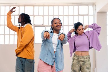 Çok ırklı hip-hop dansçılarından oluşan genç bir grup renkli sokak kıyafetleri giyip dans ediyorlar.