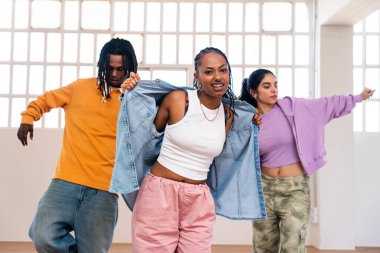 Çok ırklı hip-hop dansçılarından oluşan genç bir grup renkli sokak kıyafetleri giyip dans ediyorlar.