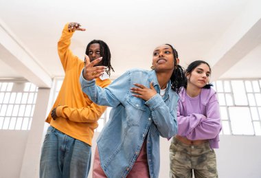 Çok ırklı hip-hop dansçılarından oluşan genç bir grup renkli sokak kıyafetleri giyip dans ediyorlar.