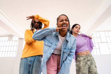 Çok ırklı hip-hop dansçılarından oluşan genç bir grup renkli sokak kıyafetleri giyip dans ediyorlar.