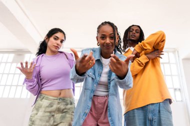 Çok ırklı hip-hop dansçılarından oluşan genç bir grup renkli sokak kıyafetleri giyip dans ediyorlar.