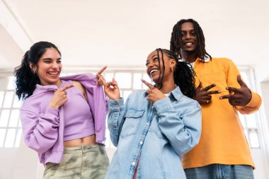 Çok ırklı hip-hop dansçılarından oluşan genç bir grup renkli sokak kıyafetleri giyip dans ediyorlar.