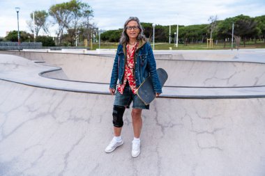 Paten parkında kaykay yapan güzel, aktif bir son sınıf öğrencisi kadın kaykaycı olgun bir kadın kaykaycı eğleniyor, yaşlılar, modern yaşam tarzı ve yeşil hareketlilik kavramları var.