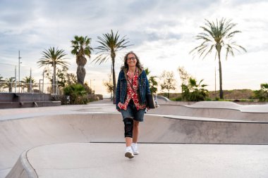 Paten parkında kaykay yapan güzel, aktif bir son sınıf öğrencisi kadın kaykaycı olgun bir kadın kaykaycı eğleniyor, yaşlılar, modern yaşam tarzı ve yeşil hareketlilik kavramları var.